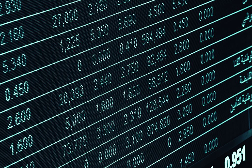 Stock ticker boards scrolling green and red market numbers — the raw surface that news-sentiment models try to read.
