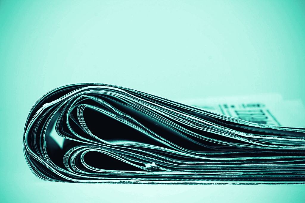 A stack of broadsheet newspapers — the corpus that news-sentiment models are trained and tested on.